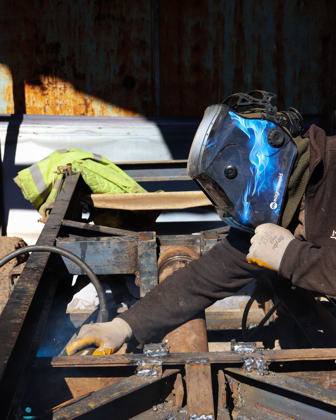 Welder in a helmet welding a steel frame